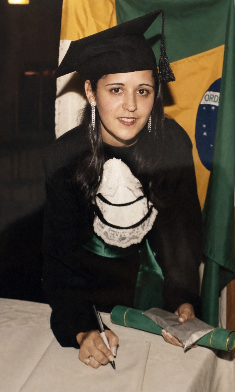 Luciene em sua formatura, assinando o diploma